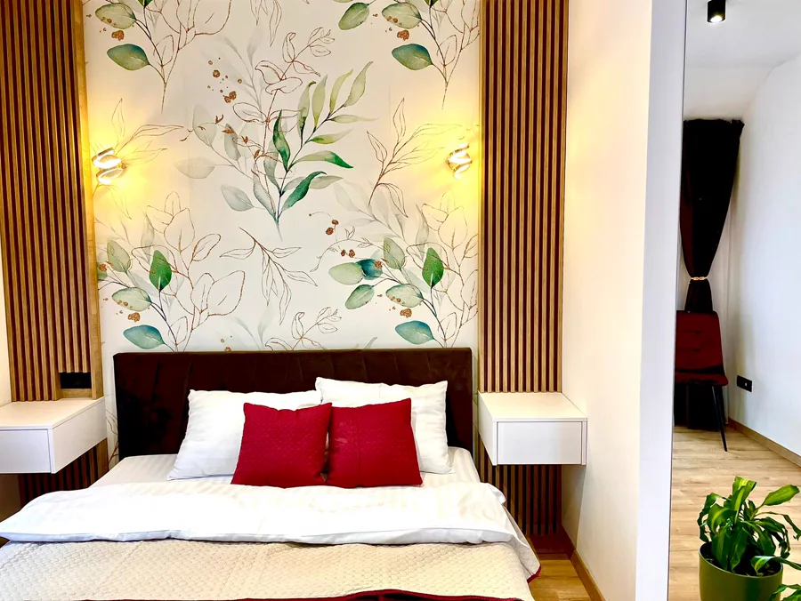 Bedroom with botanical wallpaper and white curtains — warm lighting